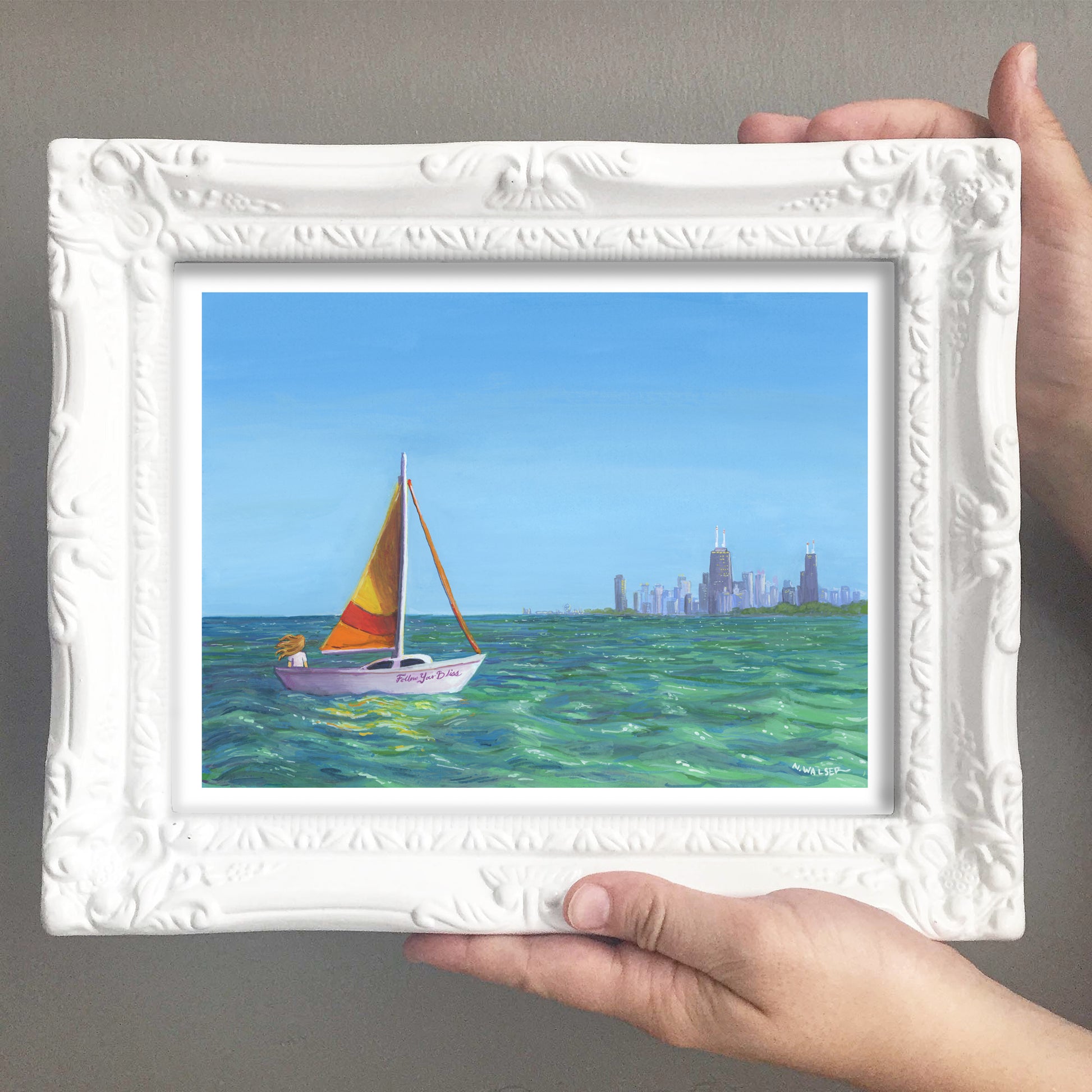 Framed painting of a sailboat on water with a city skyline in the background
