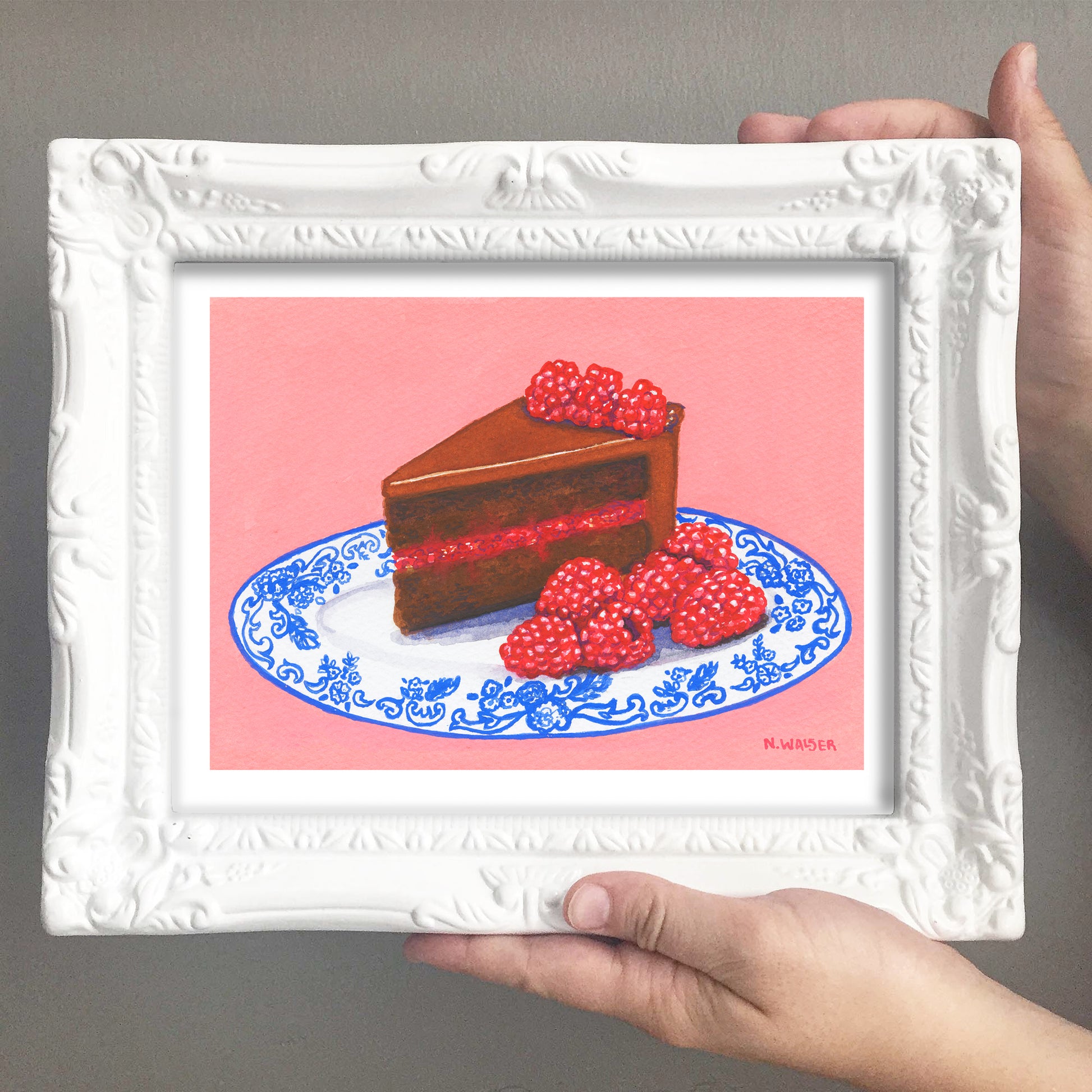 Framed artwork of a slice of chocolate cake with raspberries on a pink background