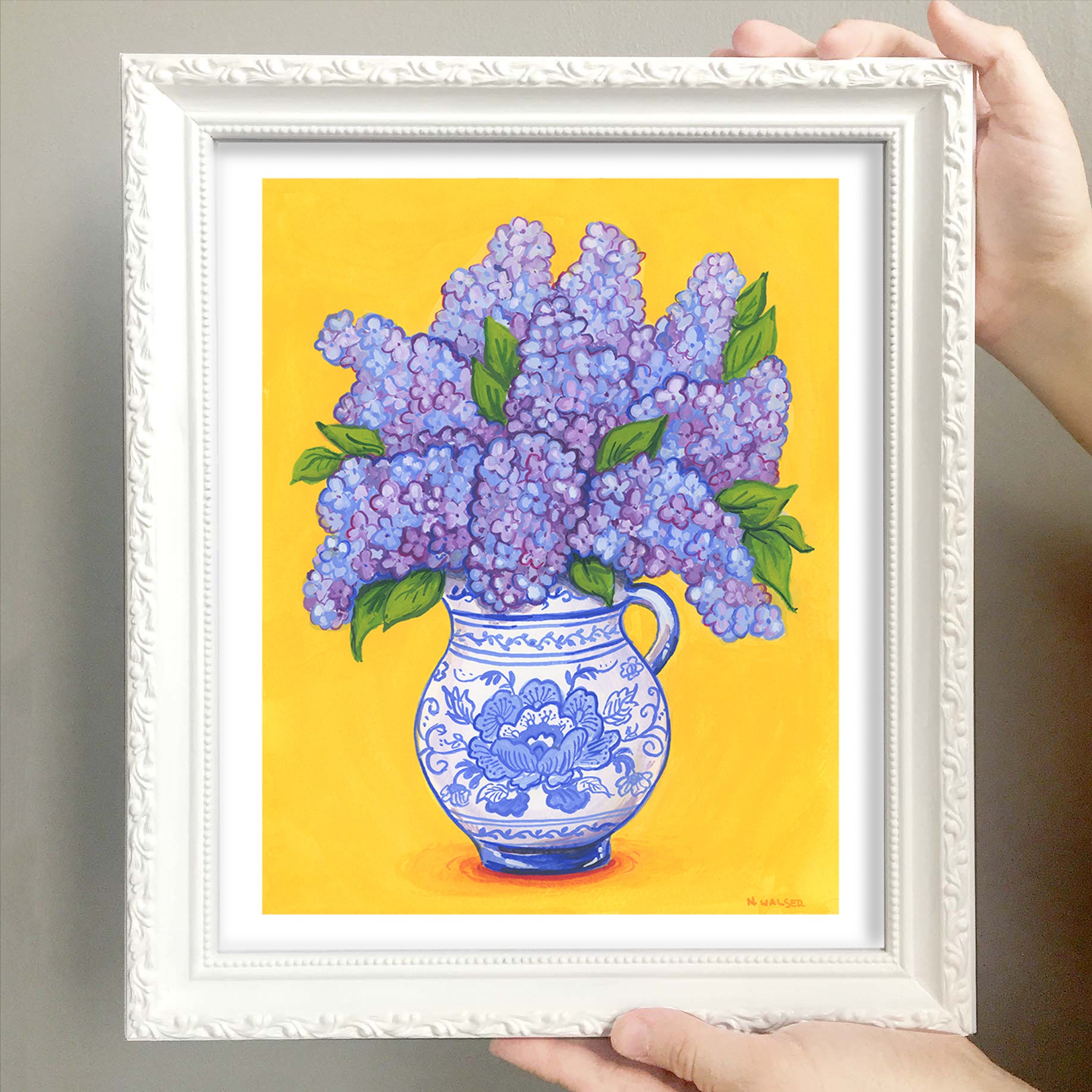 Framed artwork of a blue vase with purple flowers on a yellow background