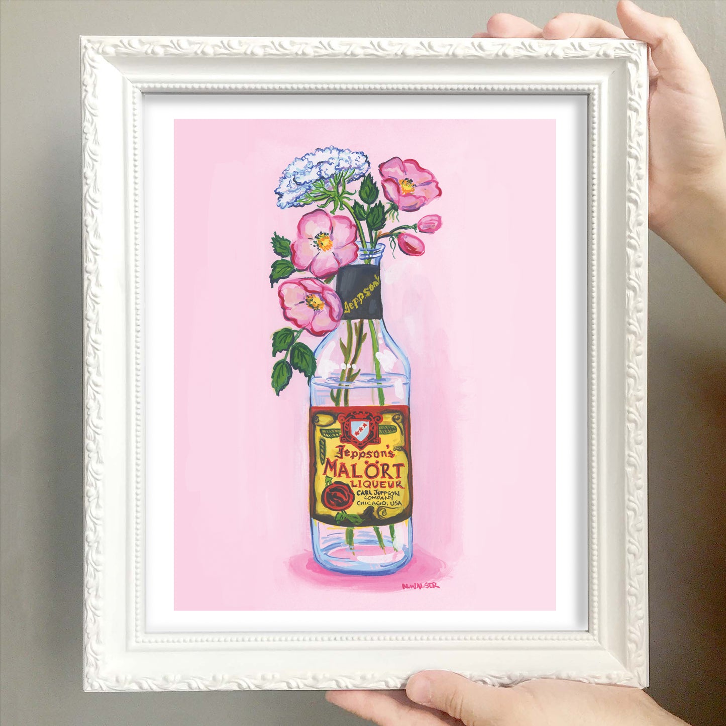 Framed artwork of flowers in a bottle with a Malort label on a pink background