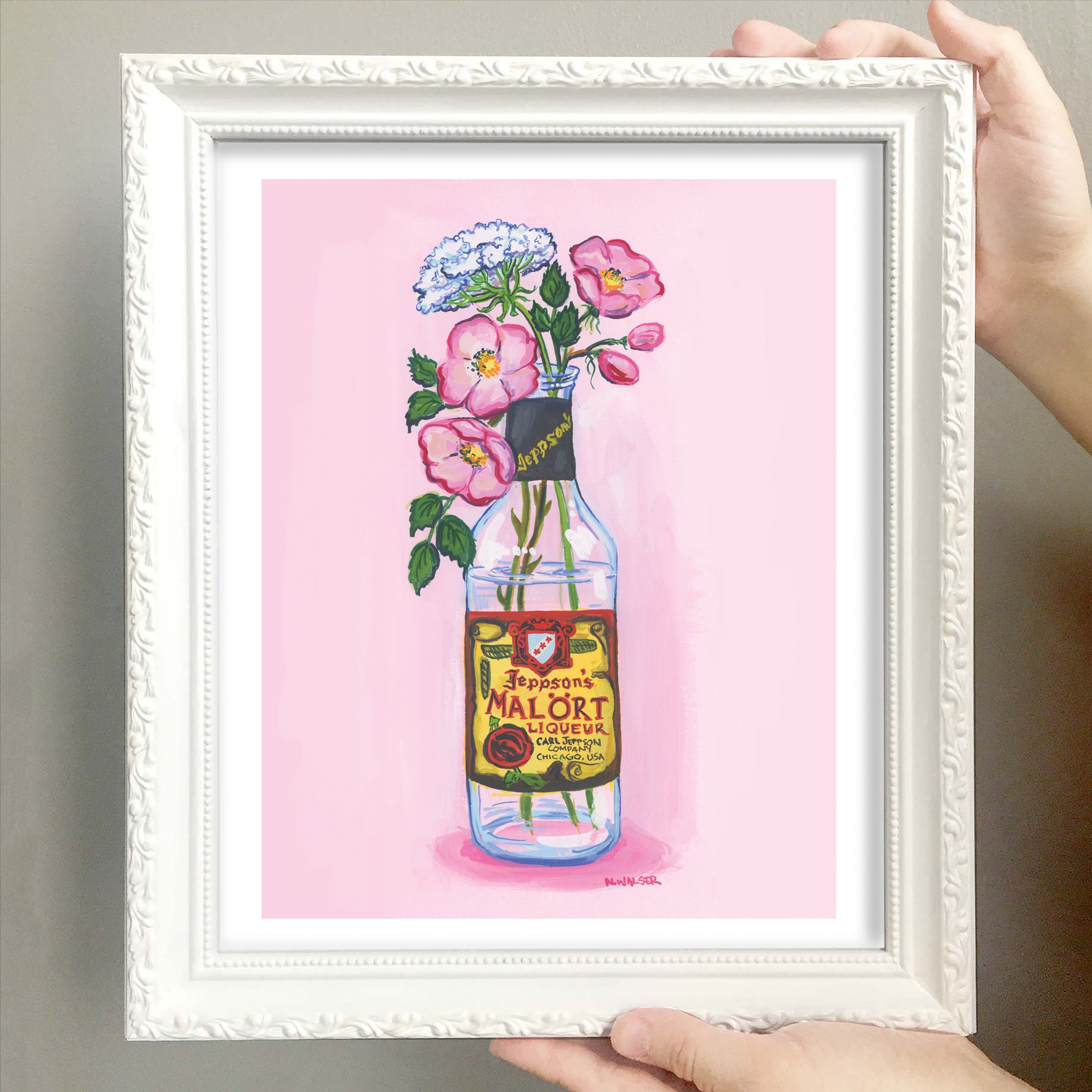 Framed artwork of flowers in a bottle with a Malort label on a pink background