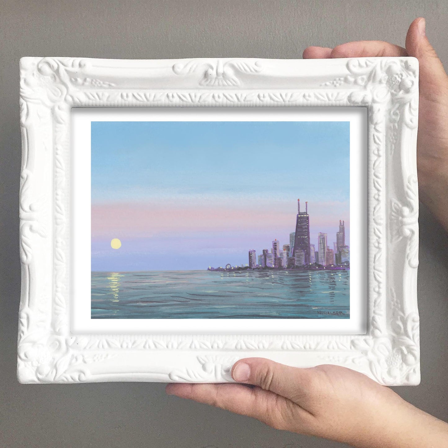 Framed artwork of a city skyline over water with the moon rising