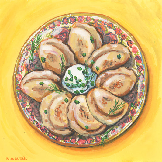 Decorative plate with pierogi and sour cream on a yellow background