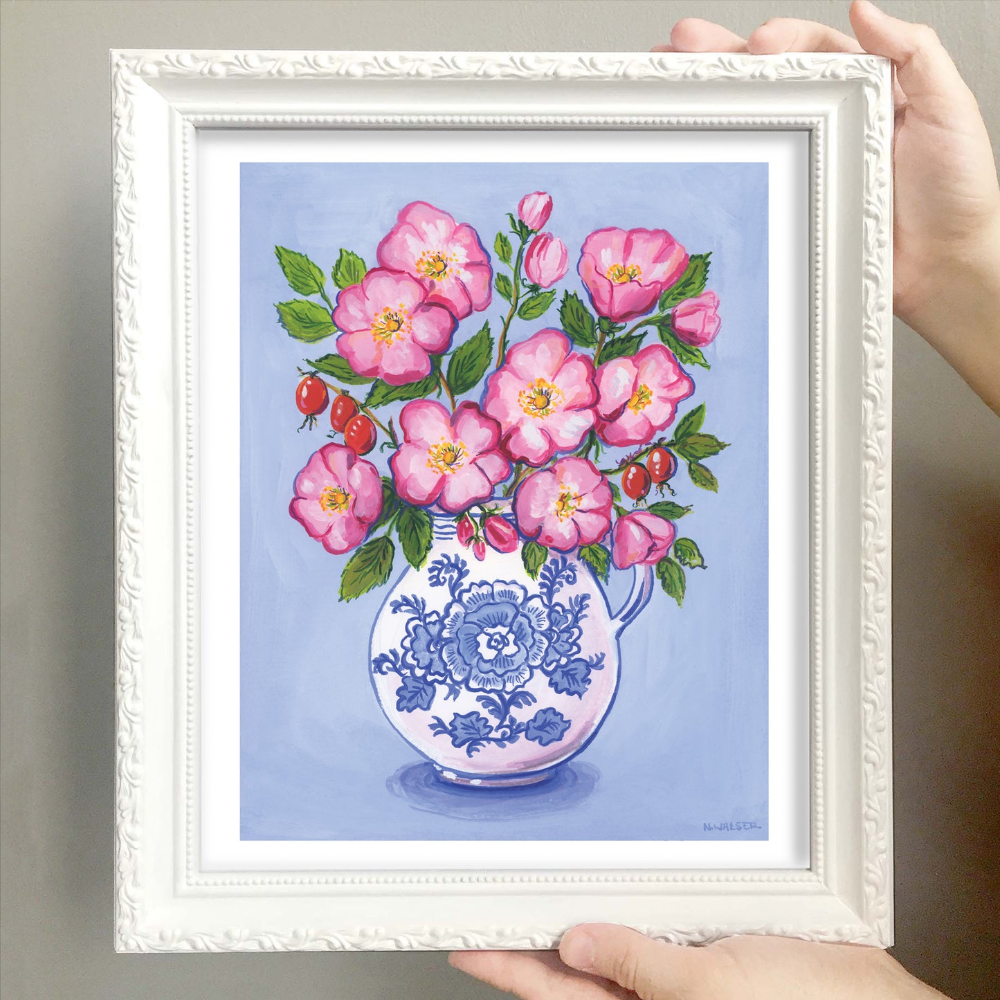 Framed artwork of pink flowers in a blue and white vase on a light blue background