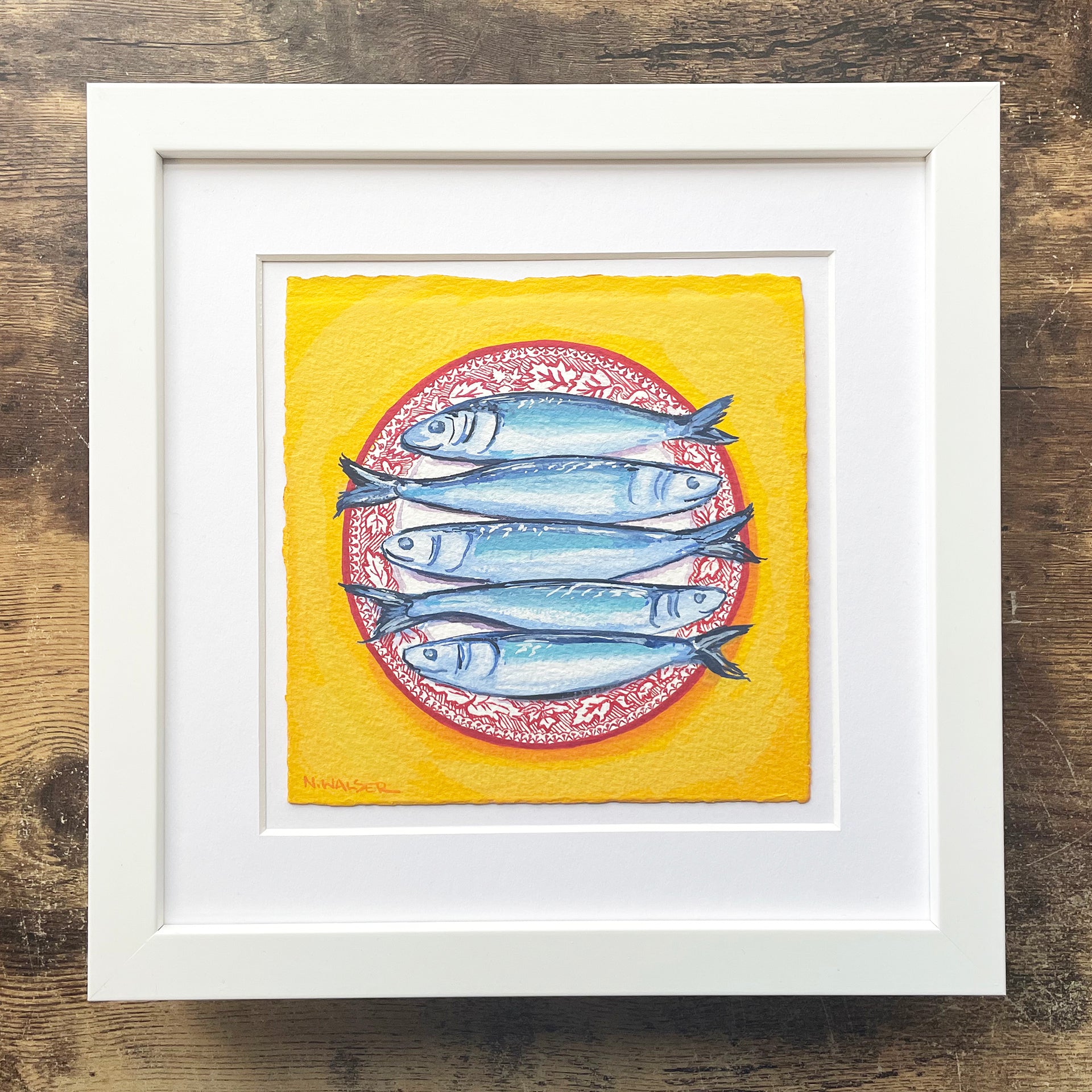 Framed artwork of fish on a yellow background with a white frame.