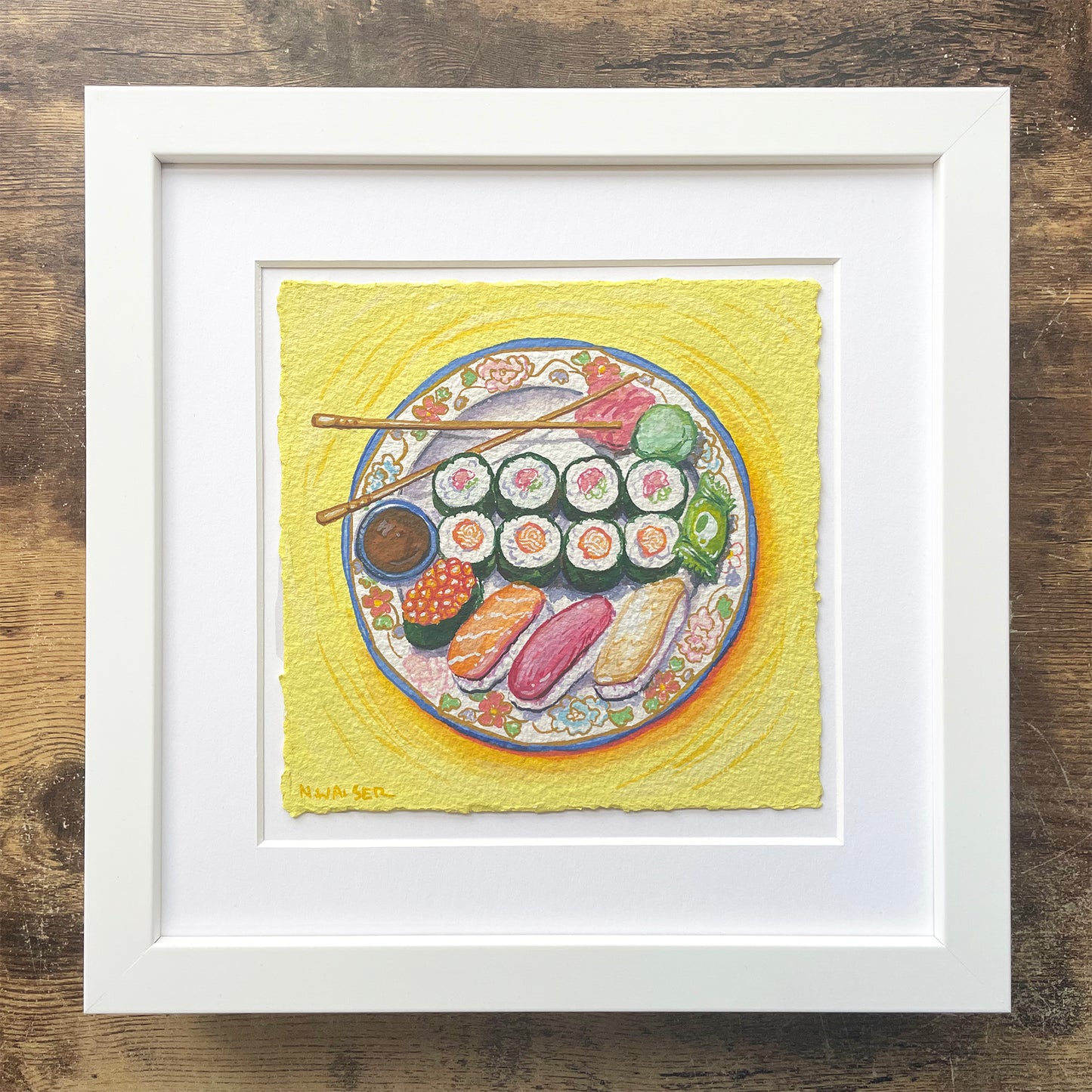 Framed artwork of a plate of sushi on a yellow background
